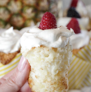 pineapple angel food cake cupcake unwrapped with cool whip and raspberry on top
