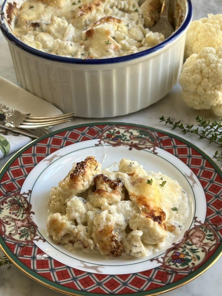 low carb keto side dish cauliflower gratin recipe serving on a plate with baking dish behind