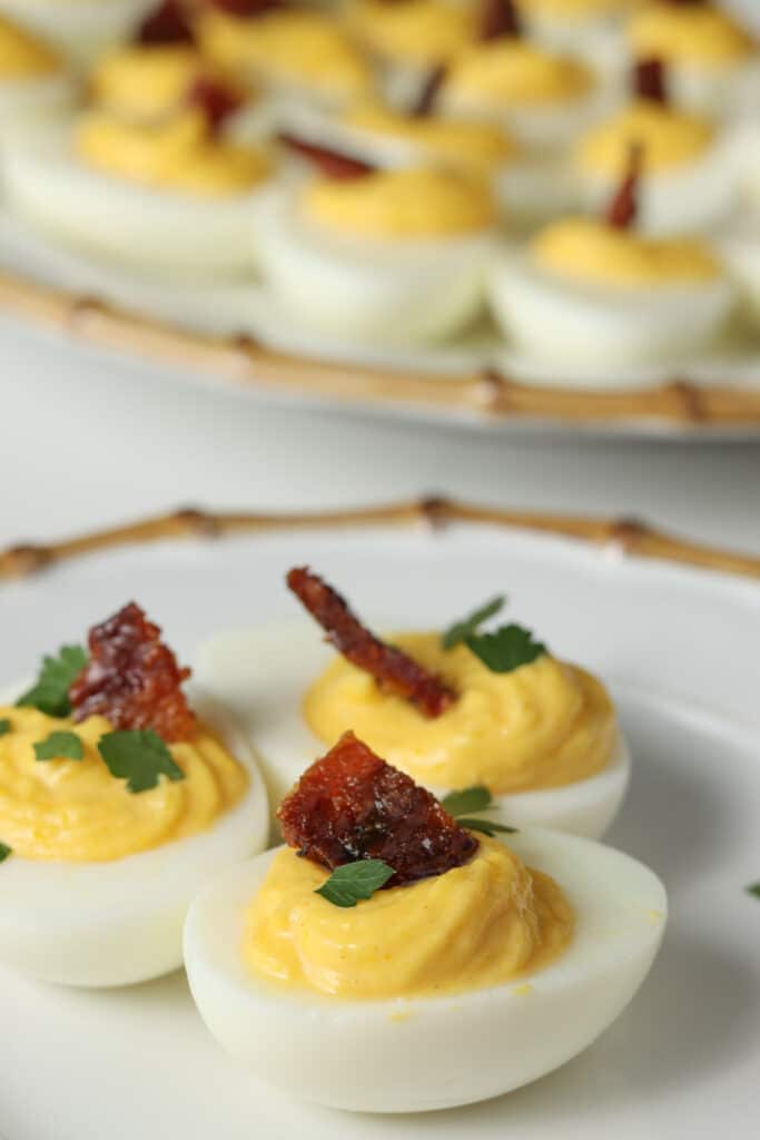 deviled eggs on white plate with candied bacon