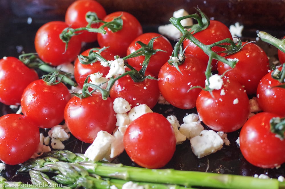 Clusters of bright red cherry tomatoes with the stems. Feta scattered around them with the braised asparagus