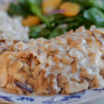 chicken breast smothered in morel mushroom sauce with rice and spinach salad on a plate