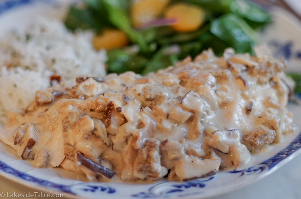 chicken breast smothered in morel mushroom sauce with rice and spinach salad on a plate