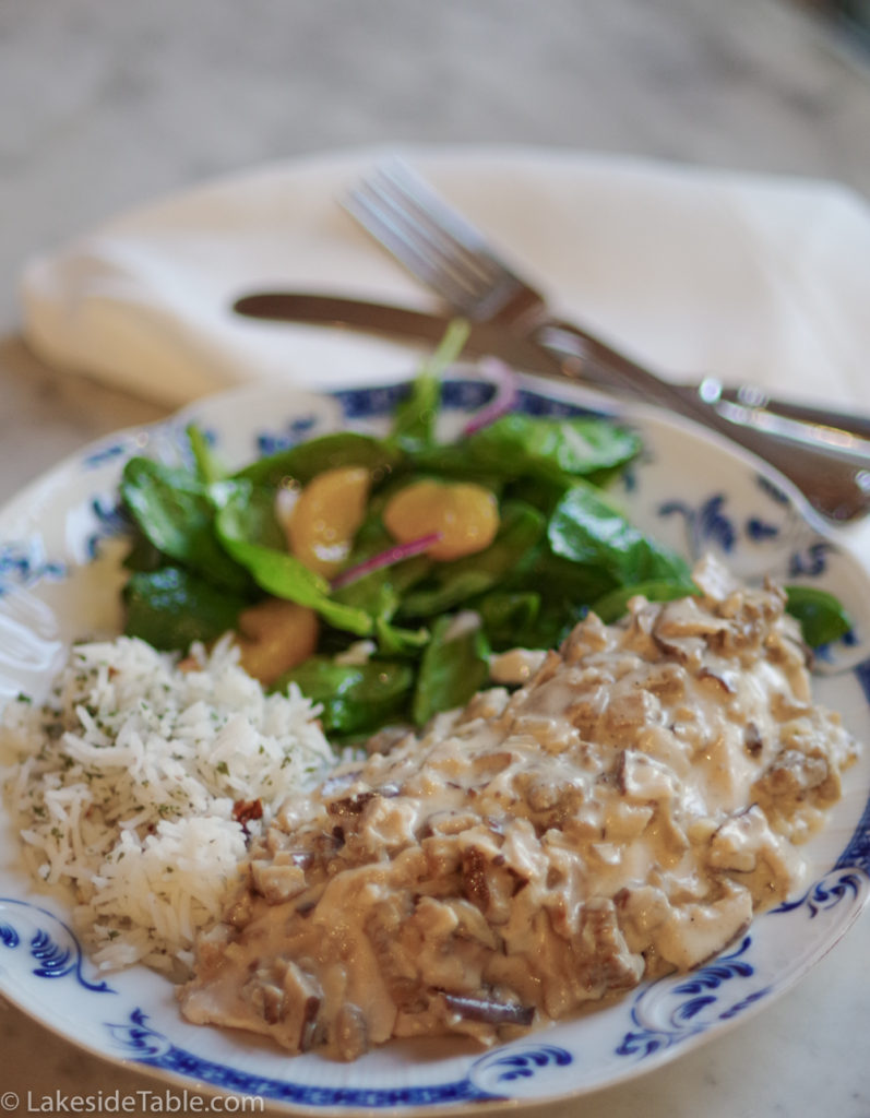 chicken breast smothered in morel mushroom sauce with rice and spinach salad on a plate is creamy just like a creamy apricot tart