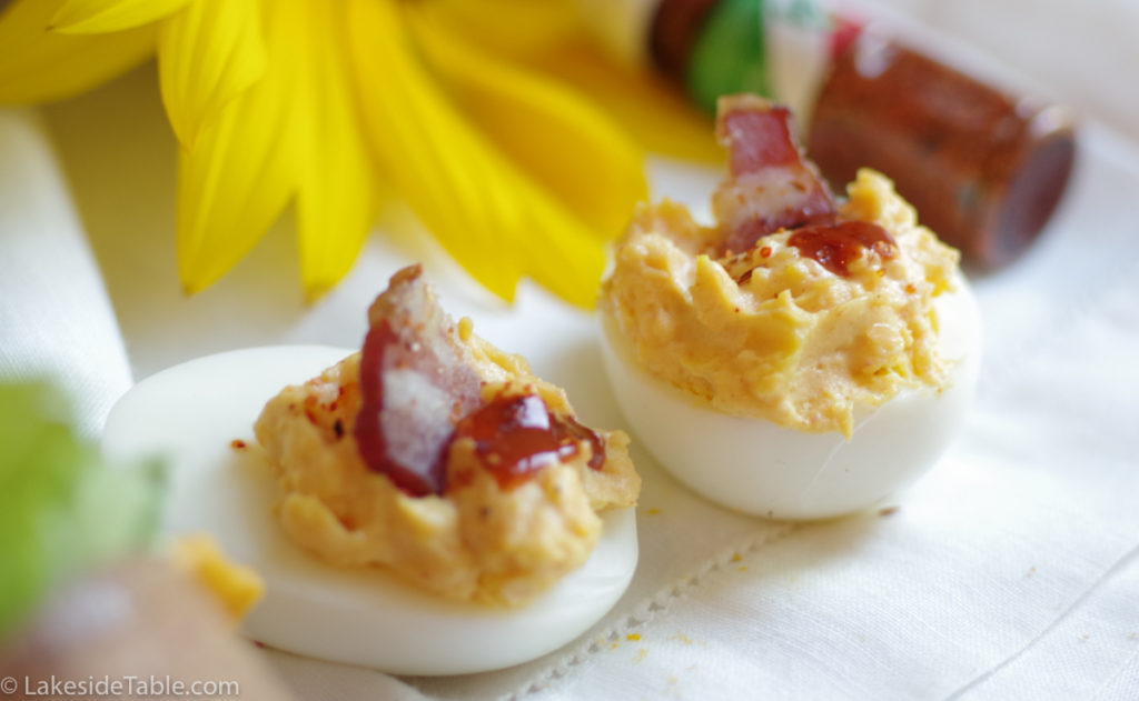 2 deviled eggs with bacon and hot sauce