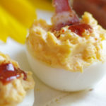 2 deviled eggs with bacon and hot sauce