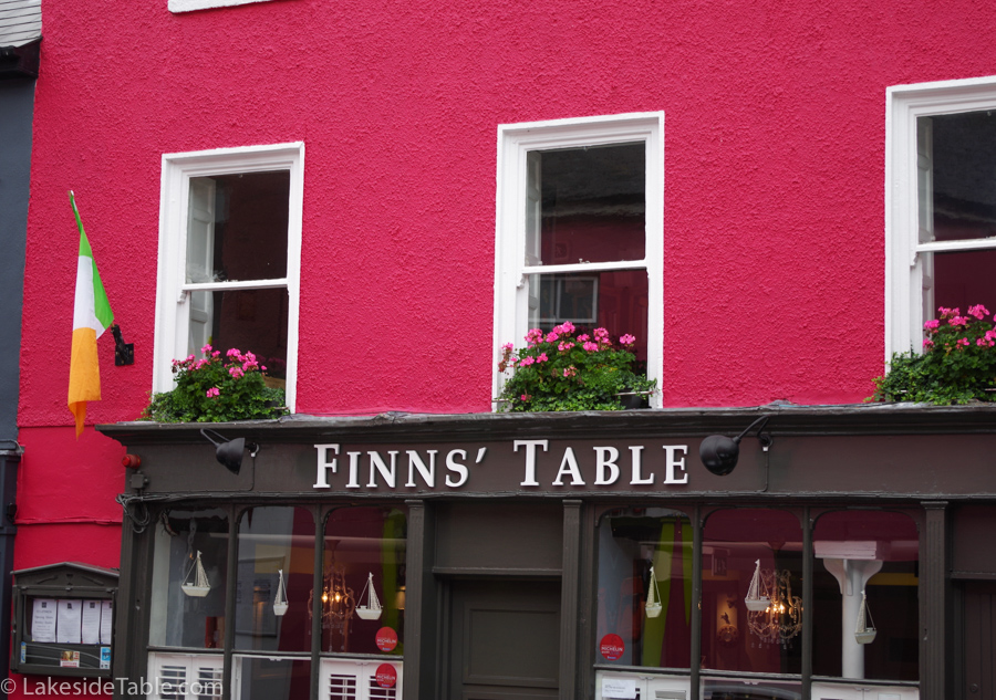the front of Finns' Table restaurant is hot pink with flower boxes full of pink geraniums in the windows above the door.
