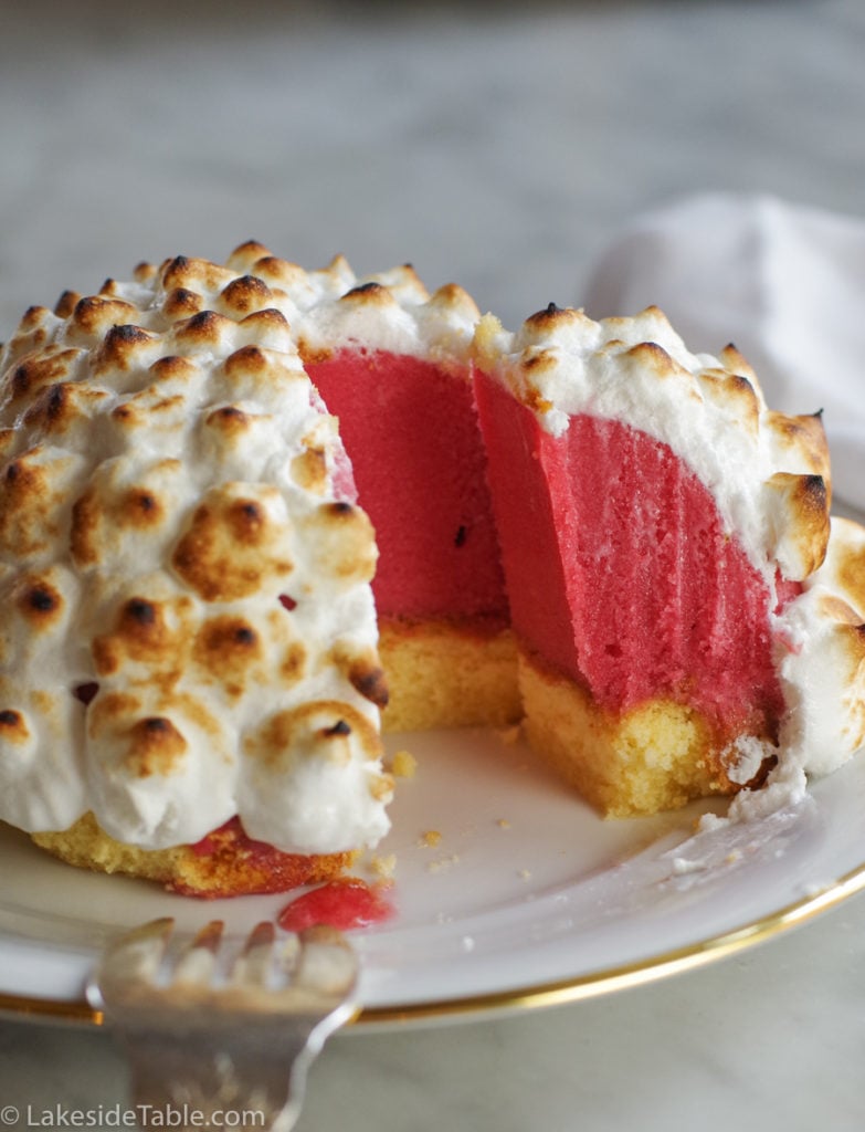 ice cream cover in toasted meringue over yellow pound cake on a white plate.