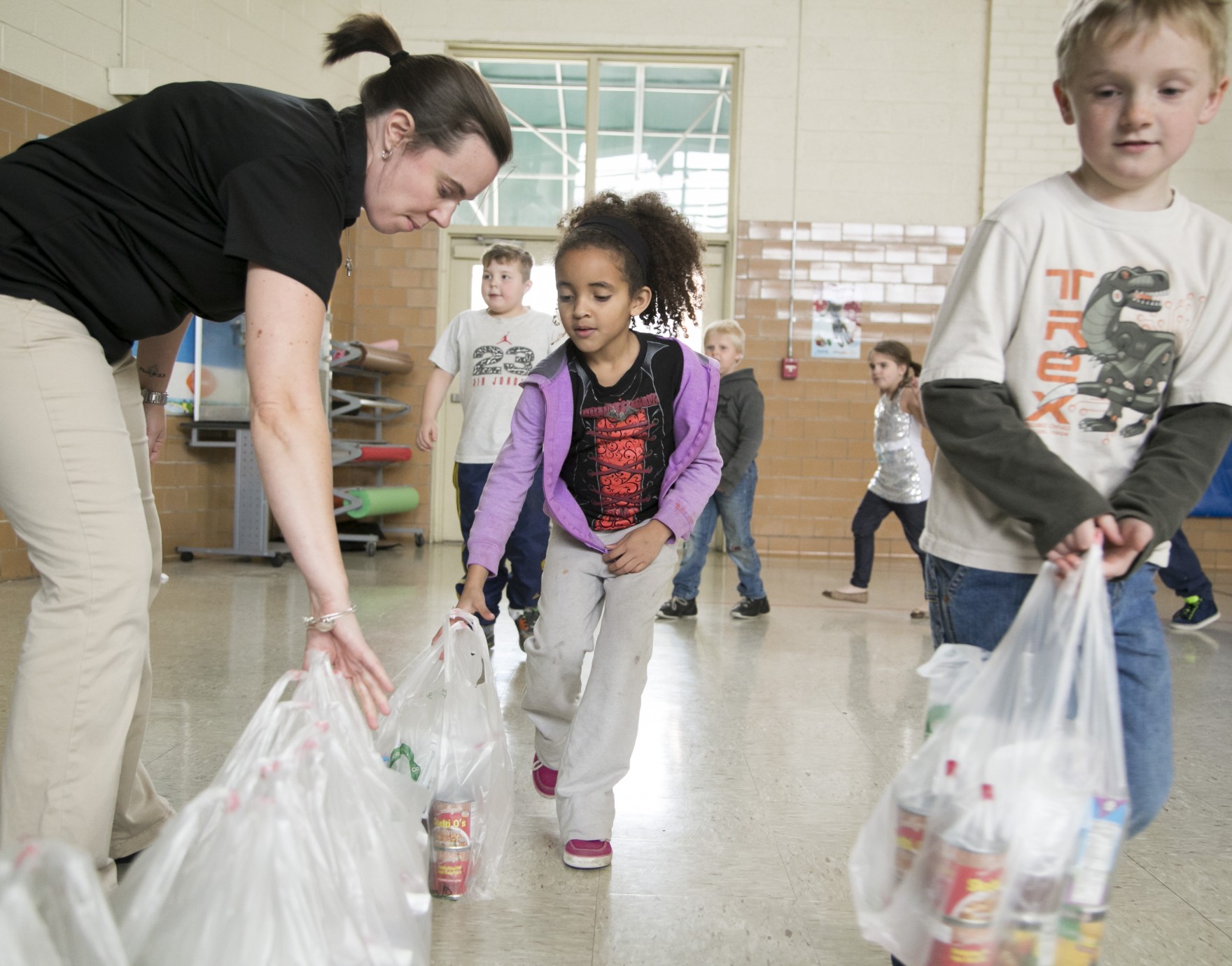 teacher helping kids bag food