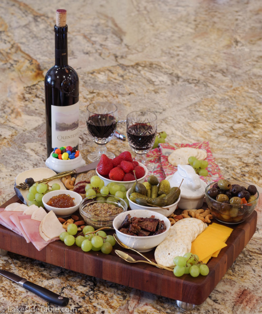 A cutting board loaded down with tons of meats, cheese, fruit and nuts