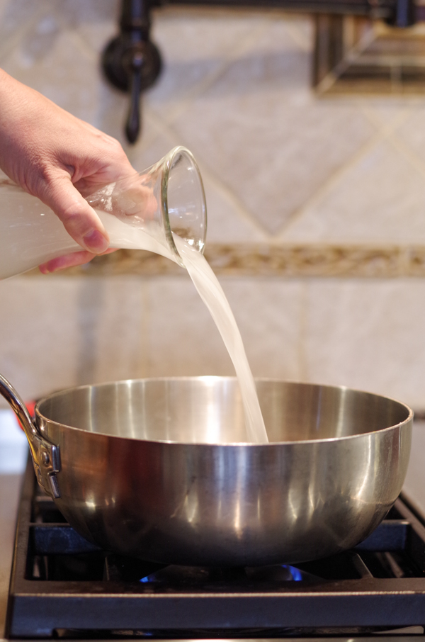 pouring coconut water into pan on stove