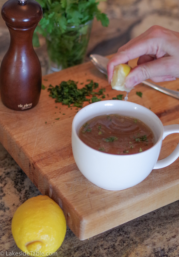 squeezing lemon into a cup of bone broth