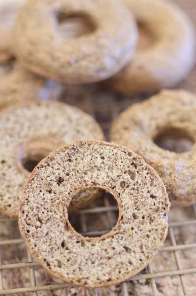 low carb bagels cooling on a cooling rack, one is sliced so you can see the multi grains and how airy it is 