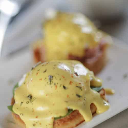 golden yellow classic hollandaise sauce over poached egg and english muffin