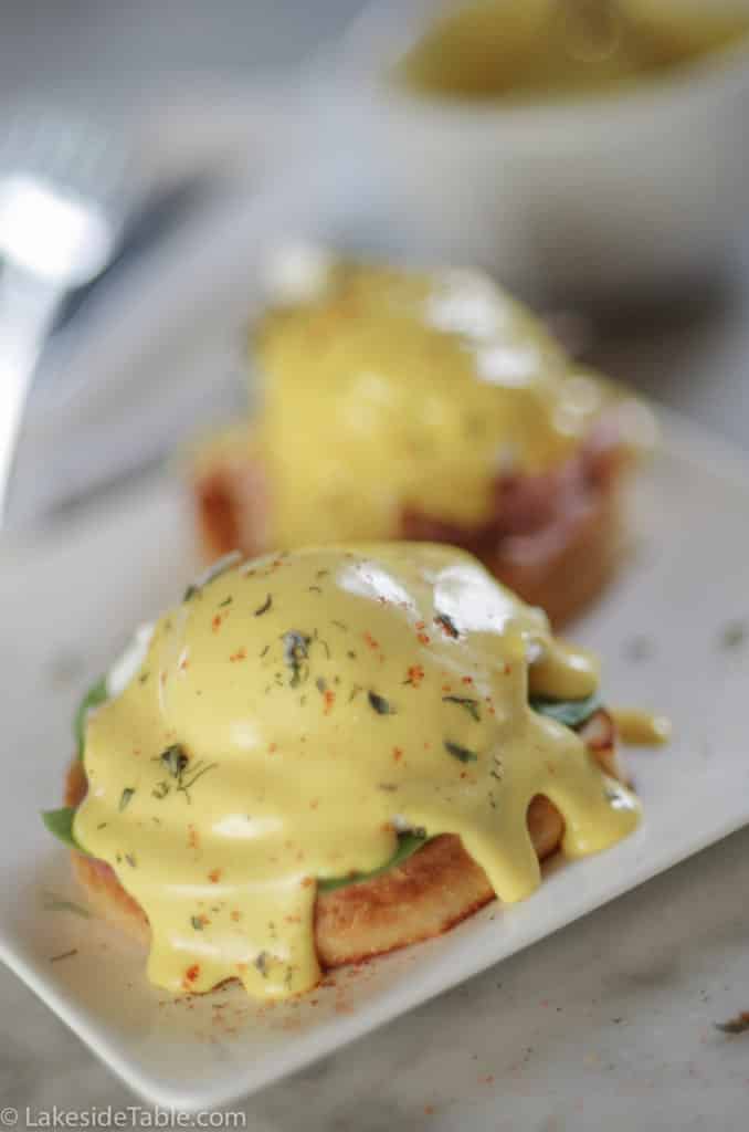 golden yellow classic hollandaise sauce over poached egg and english muffin