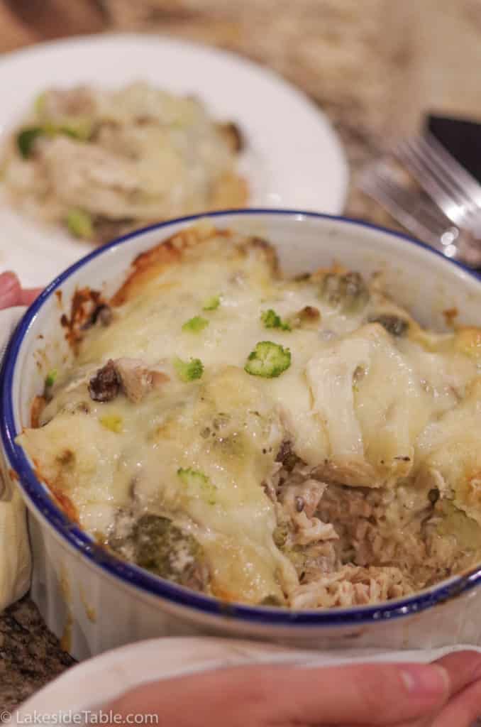 white casserole dish with white melted cheese on top of chicken and broccoli