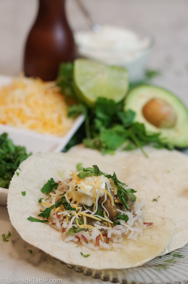pork chili verde on tortillas with cheese, avocado and lime