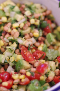 Close up of Cowboy Caviar with avocado, corn, black eye peas, tomatoes and lime