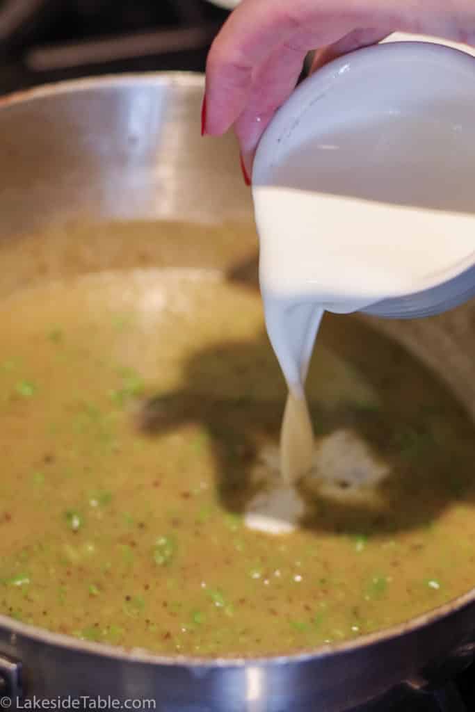 pouring white cream into pea sauce