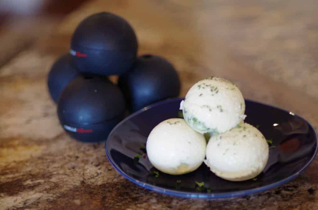 3 round white sous vide egg bites on a dark blue plate with 4 round ice molds stacked up behind them 