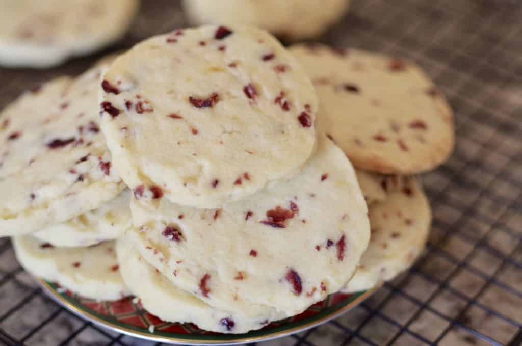 plated cookies in a pile full of cranberries and speckled with orange zest