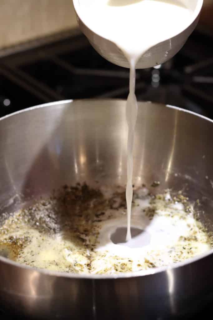 pour milk into sauce for adult mac and cheese