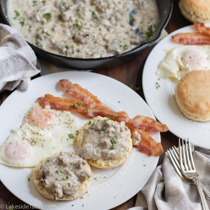 biscuit breakfast of eggs, bacon, biscuits and gravy on a plate with gravy in the background