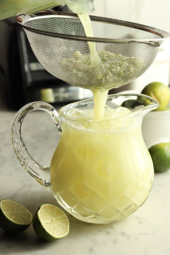 straining limeade into pitcher
