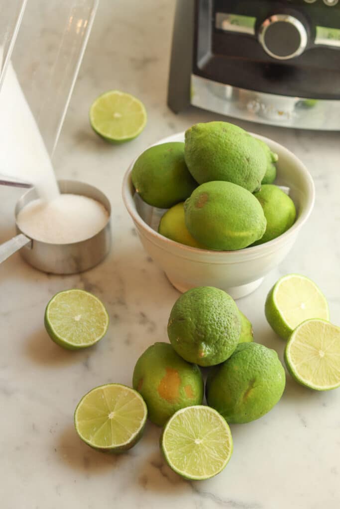 lots of limes in a bowl and on the counter