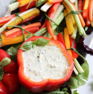 Dip for veggies in a red bell pepper with little veggie stick bundles tied with chives