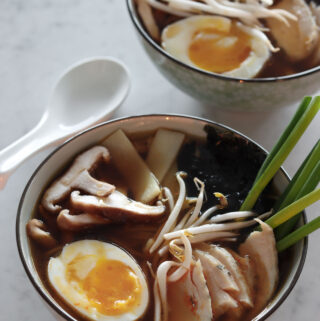 two bowls of ramen with soft boiled egg, skiitake mushrooms, sprouts, and scallions