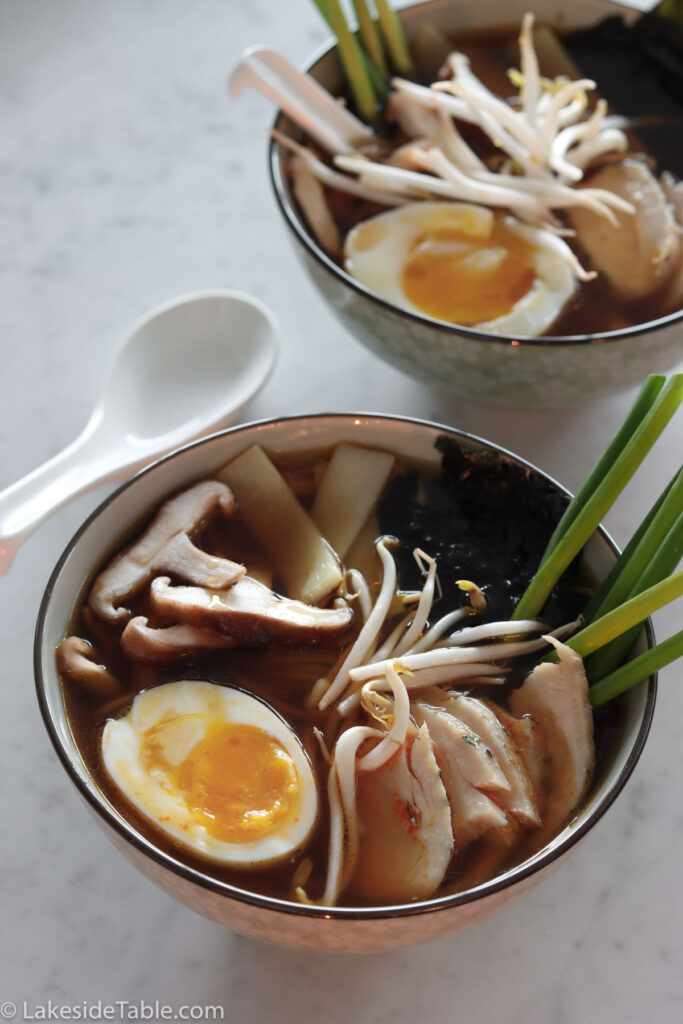 two bowls of ramen with soft boiled egg, skiitake mushrooms, sprouts, and scallions