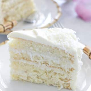 slice of 4 layered coconut cake with coconut filling and cream cheese icing