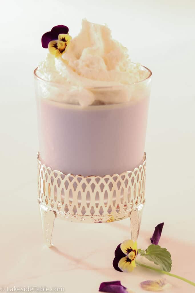 Violet panna cotta with whipped cream and fresh violet flowers