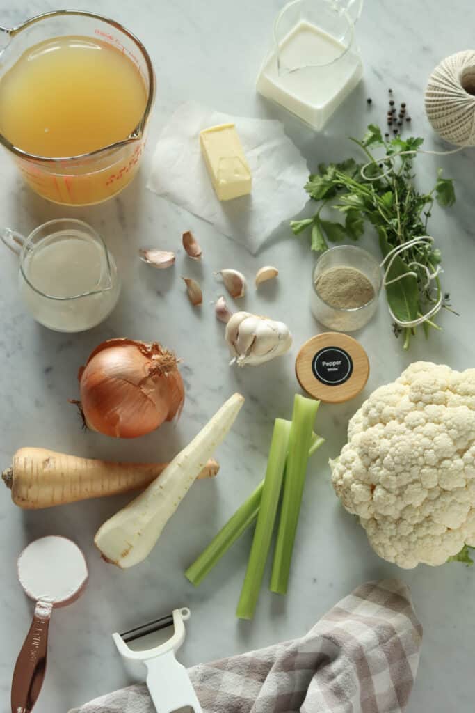 Common ingredients for cauliflower soup: cauliflower, chicken stock, onion, celery, parsnip, flour, butter, garlic, salt, white pepper, thyme, bay leaf, and parsley