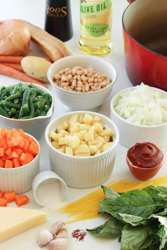 Ingredients for Soupe au Pistou laid out: potatoes, navy beans, green beans, carrots, onions, tomato paste, pasta, salt, fresh basil, garlic, and saffron