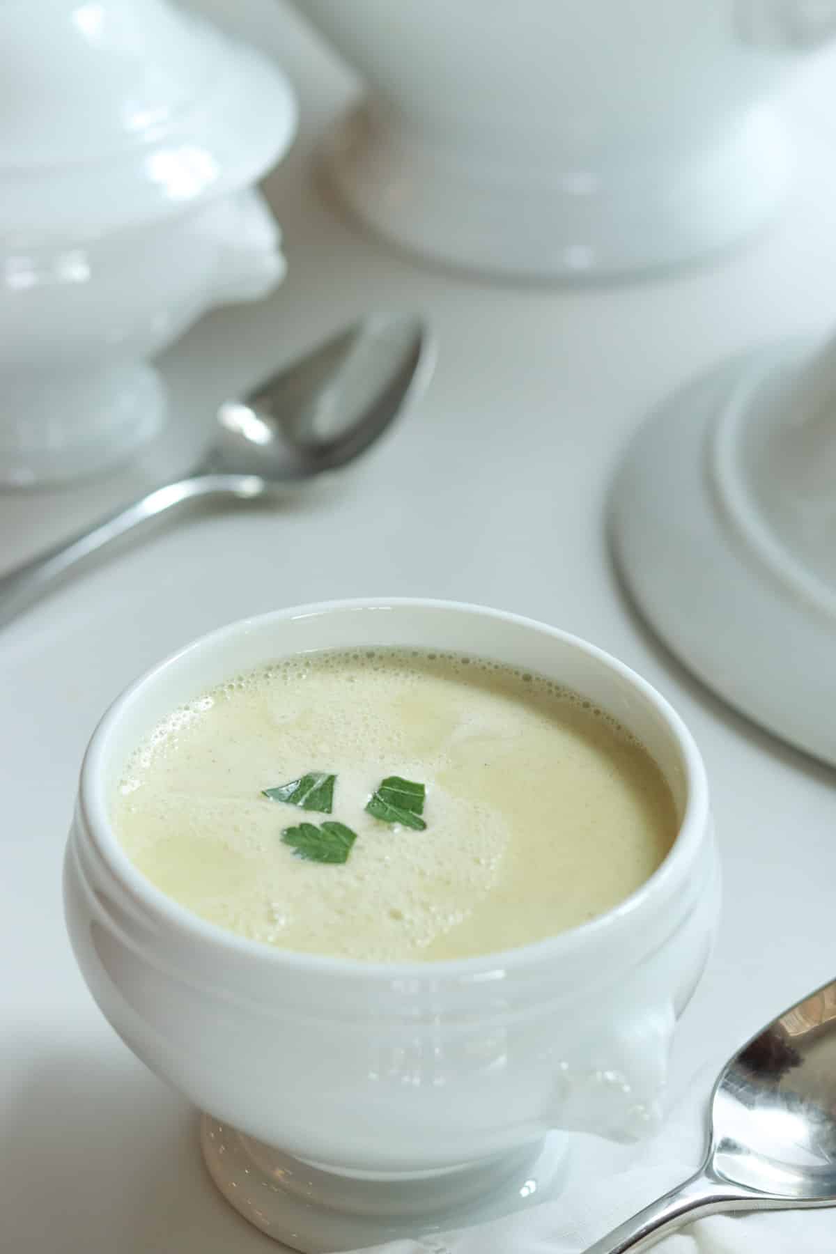 Julia Child's French Garlic Soup Aïgo Bouido in a white bowl with green parsley flakes on top