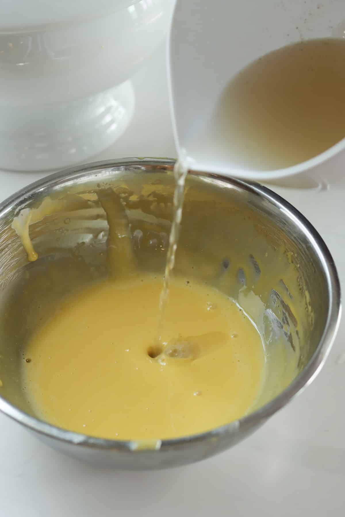 Slowly stir 1 cup of hot broth into the yolk emulsion